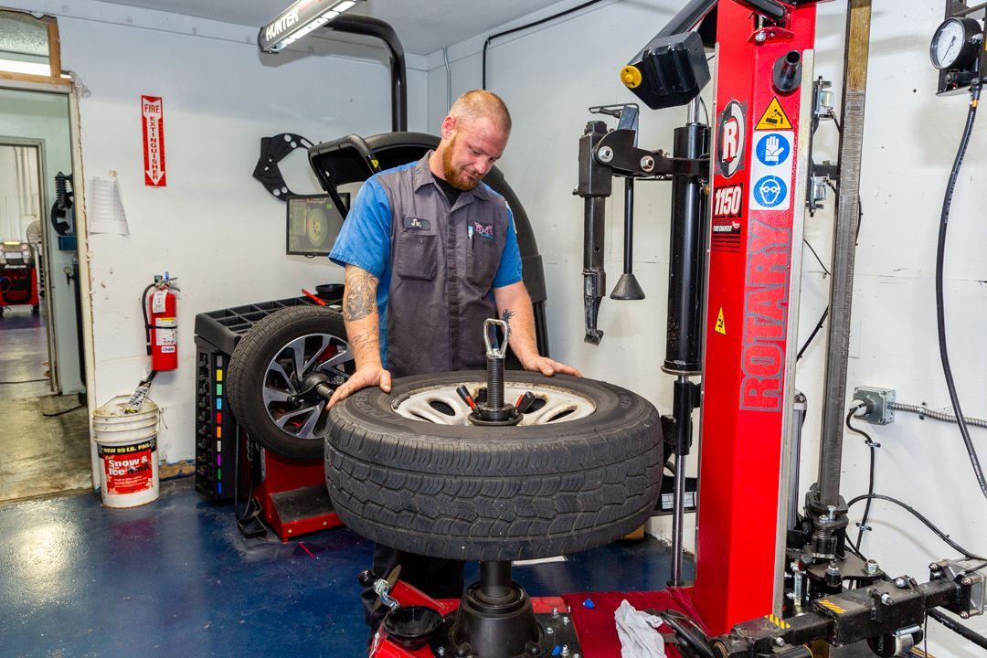A man is changing a tire on a machine in a garage.