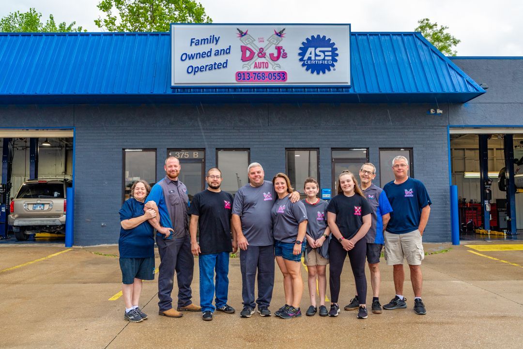 A group of people are posing for a picture in front of a garage.