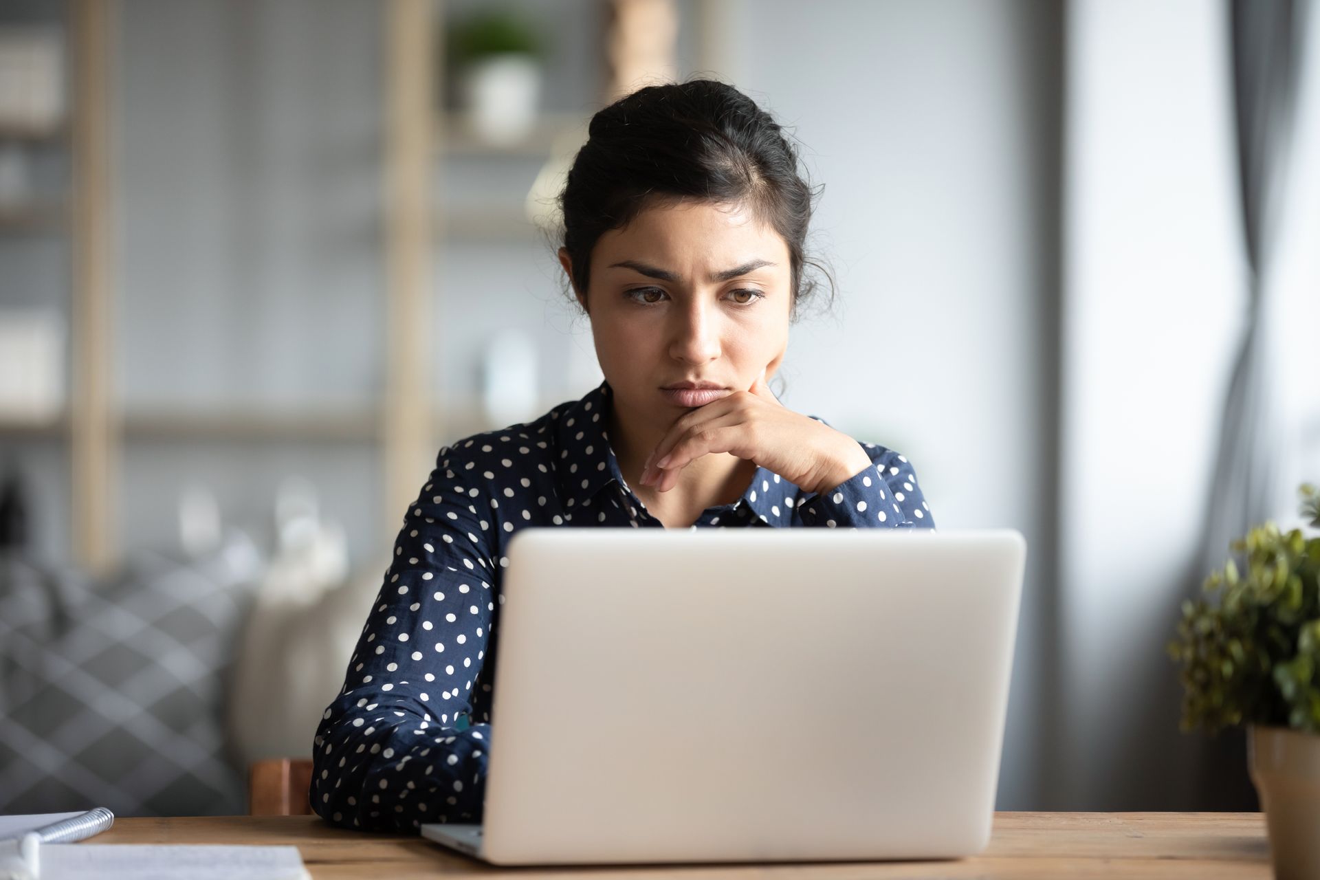 A woman is sitting at a desk using a laptop computer.