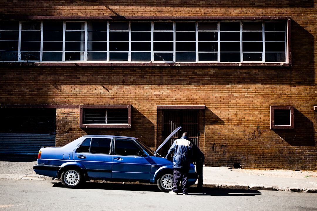 Man inspecting car with hood open outside a building for auto repair shop ads concept