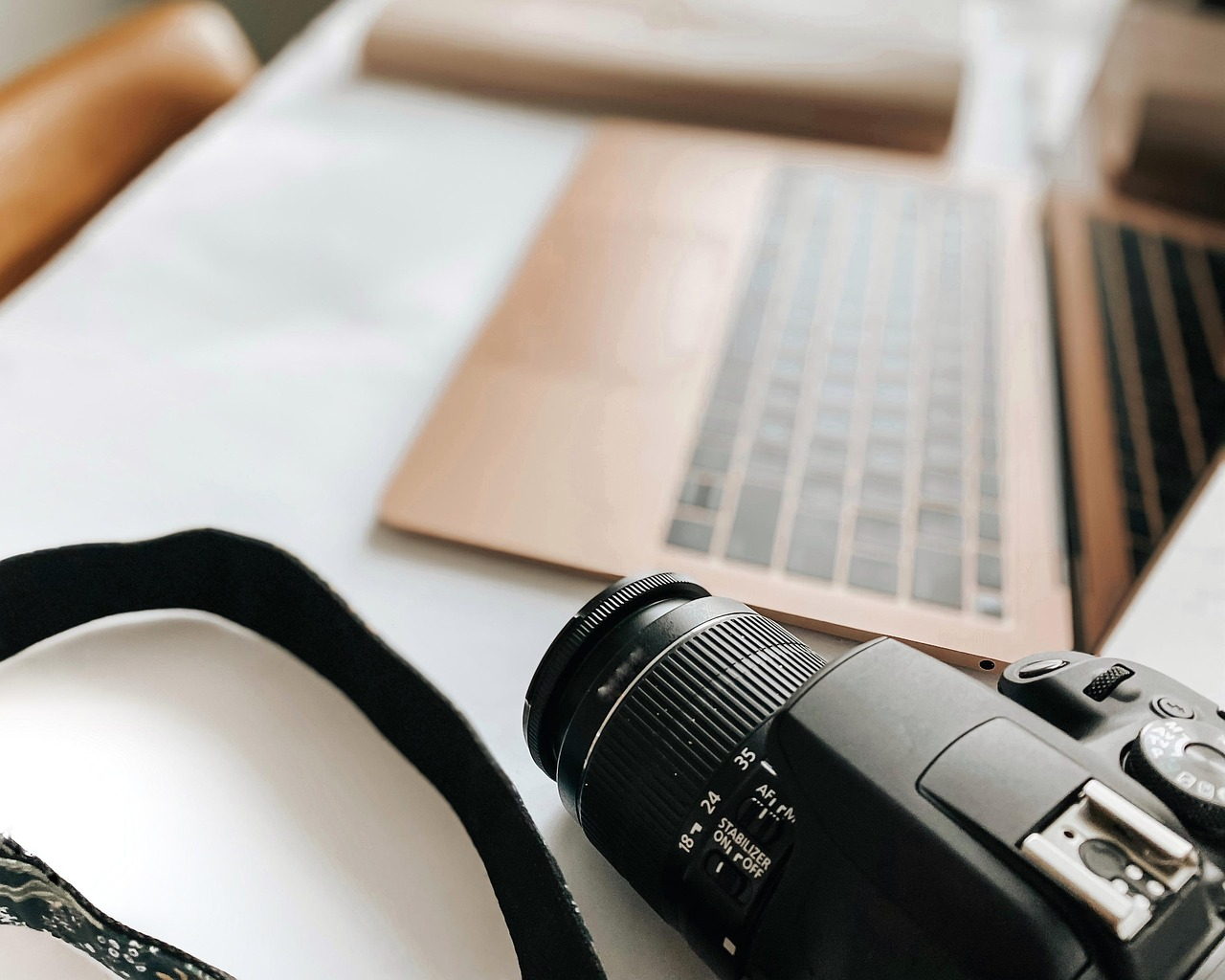 DSLR camera and laptop on a desk used for franchise marketing tasks