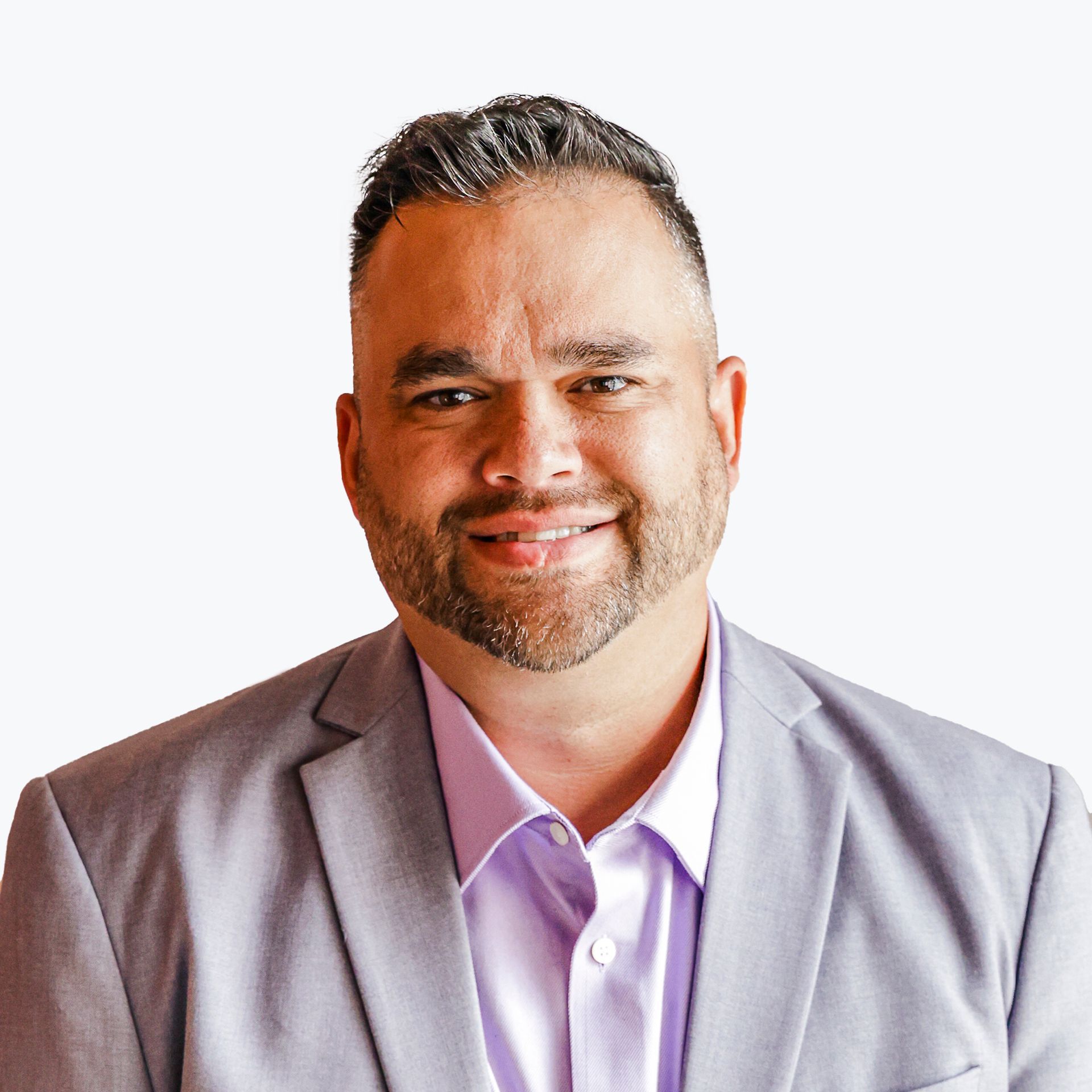 A man in a suit and purple shirt is smiling for the camera.