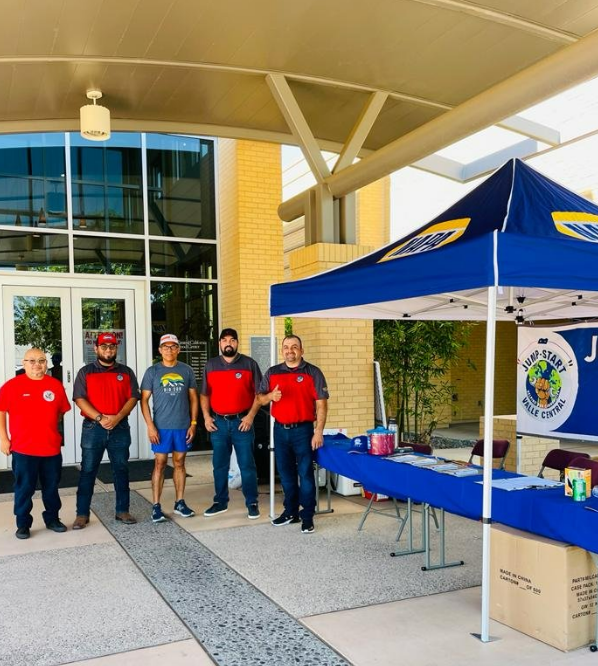 A group of men standing in front of a blue tent