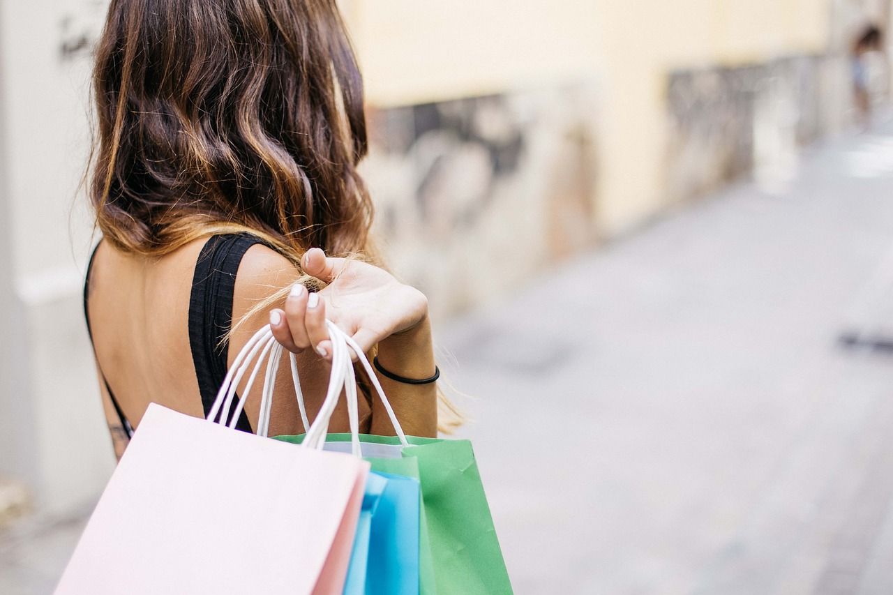 Woman holding colorful shopping bags, symbolizing consumer engagement to increase brand awareness.