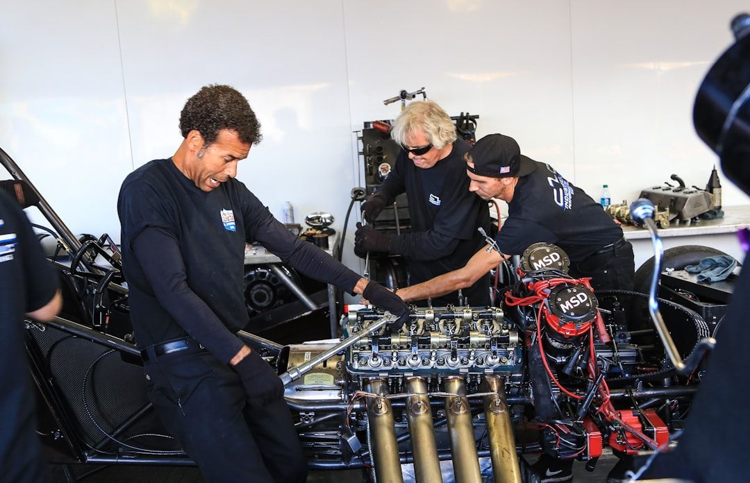 Auto repair CRM team collaborating on a high-performance engine in a garage setting
