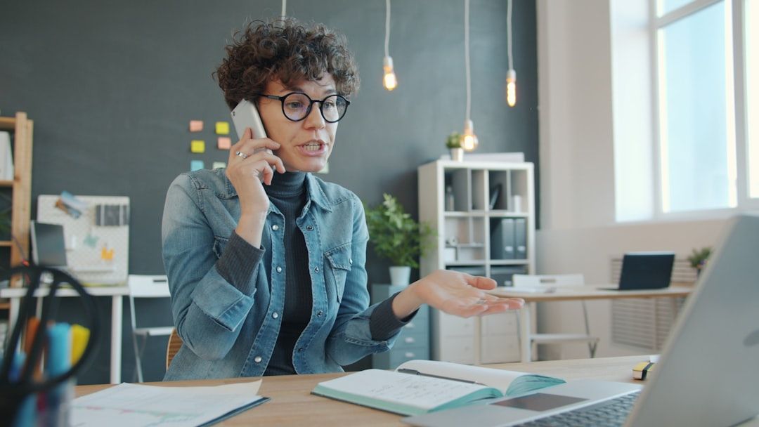 Woman on phone at desk managing a reputation crisis with concern in a modern office setting.