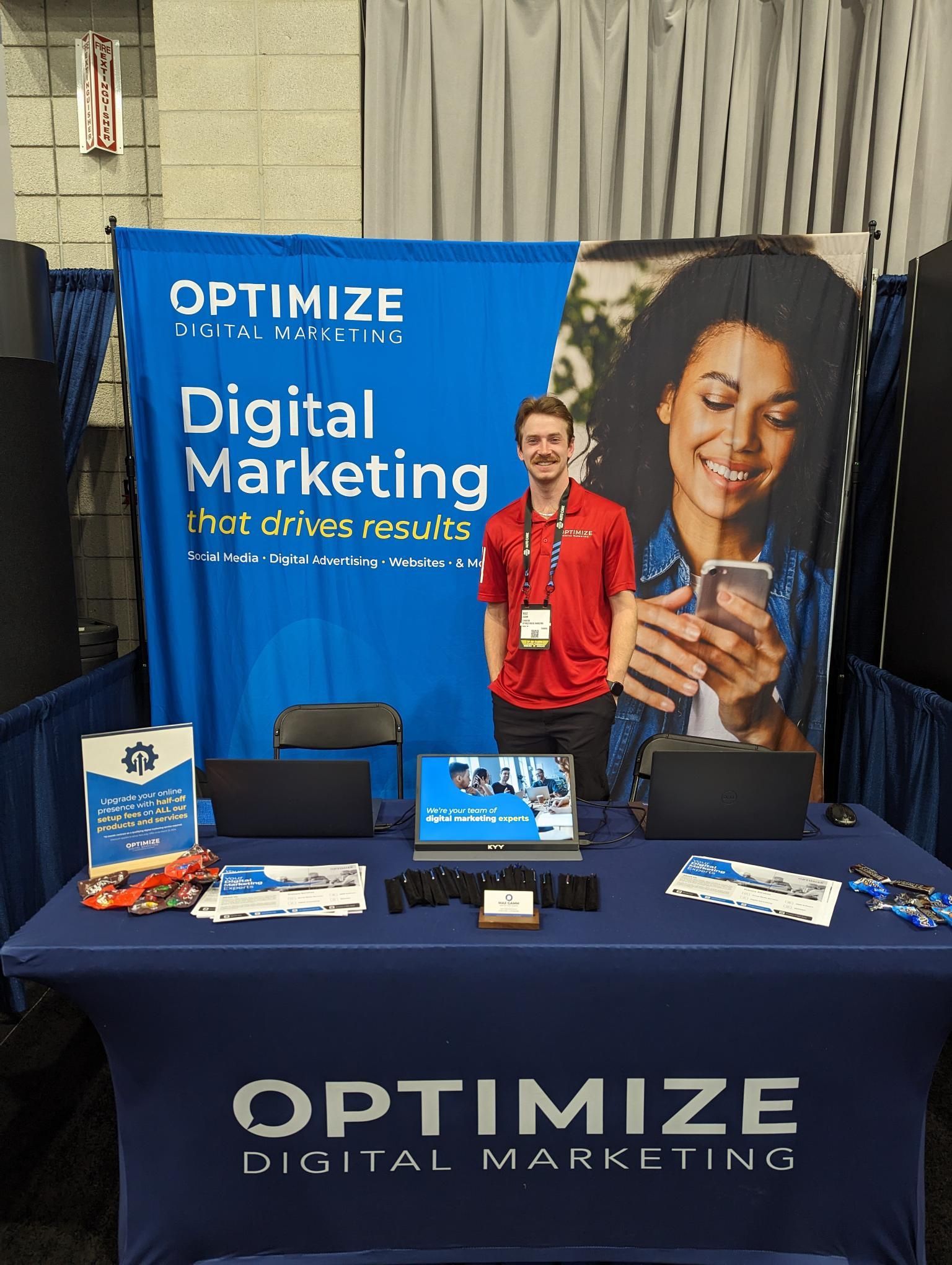 A man stands in front of a table that says optimize digital marketing