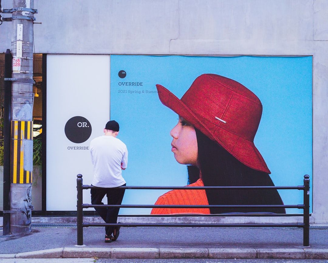 Man standing by a large fashion poster, contrasting traditional marketing with digital marketing 