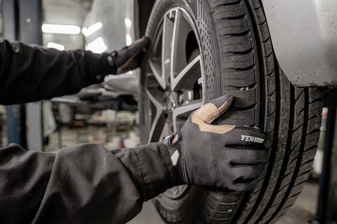 Mechanic inspecting car tire in garage, representing auto repair shop target market