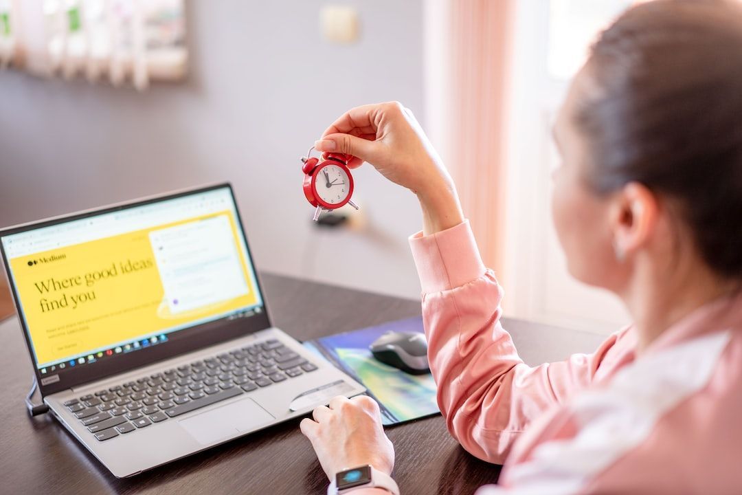 A woman holding a clock in front of a laptop evaluating how important is page speed for seo