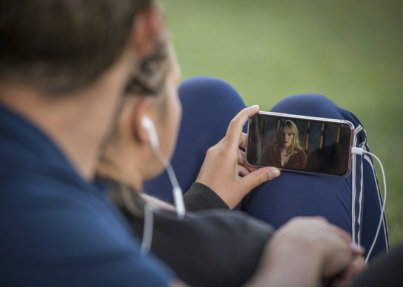 A man and a woman are watching a video advertising on a cell phone.