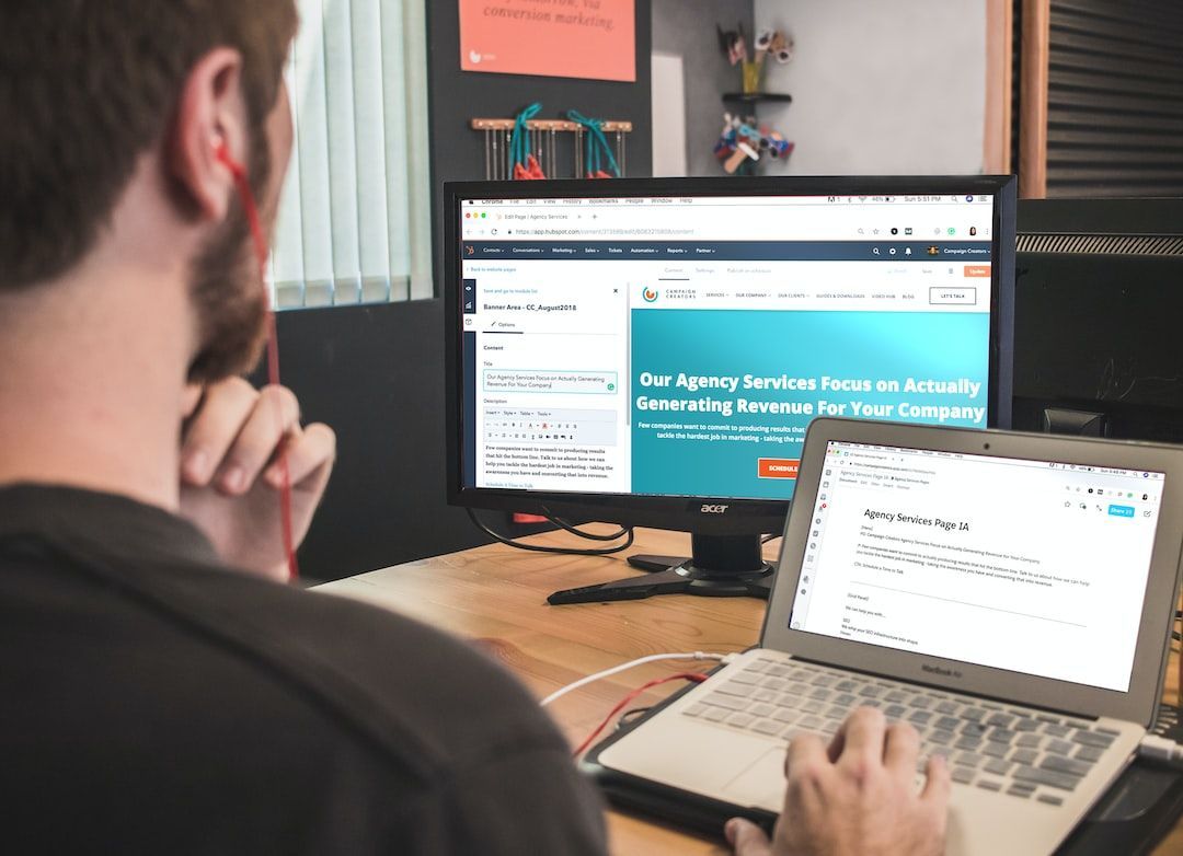 A man is sitting at a desk looking at the best marketing tools for a small business in a laptop