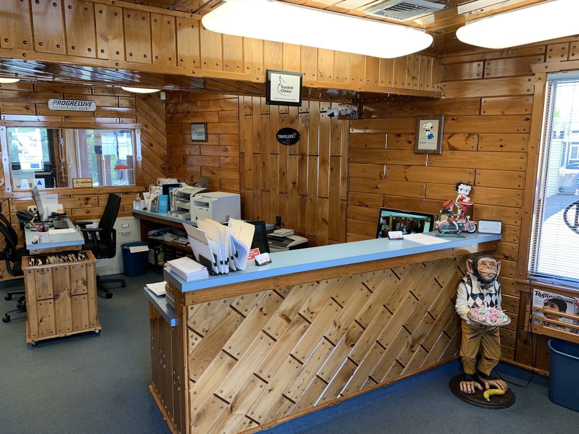 Wood-paneled office with reception desk, employees working, and a monkey statue.