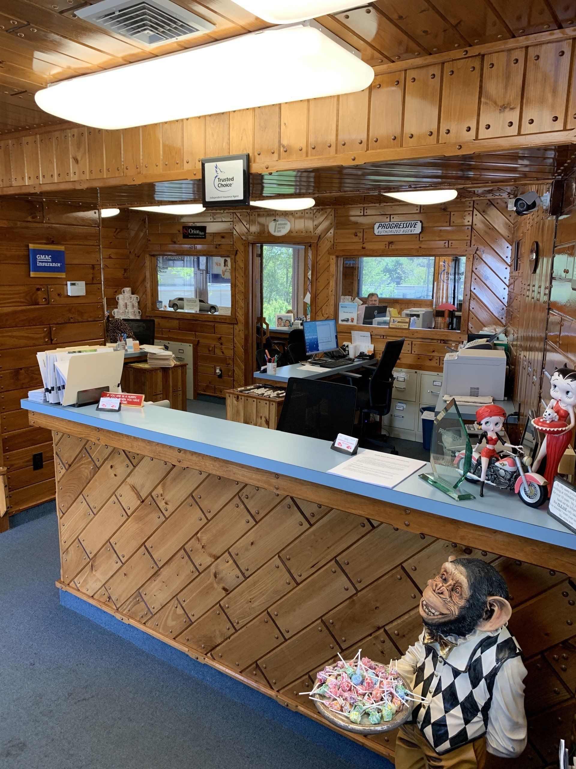 Wooden office interior with a front desk, staff working, and a monkey statue holding candy.