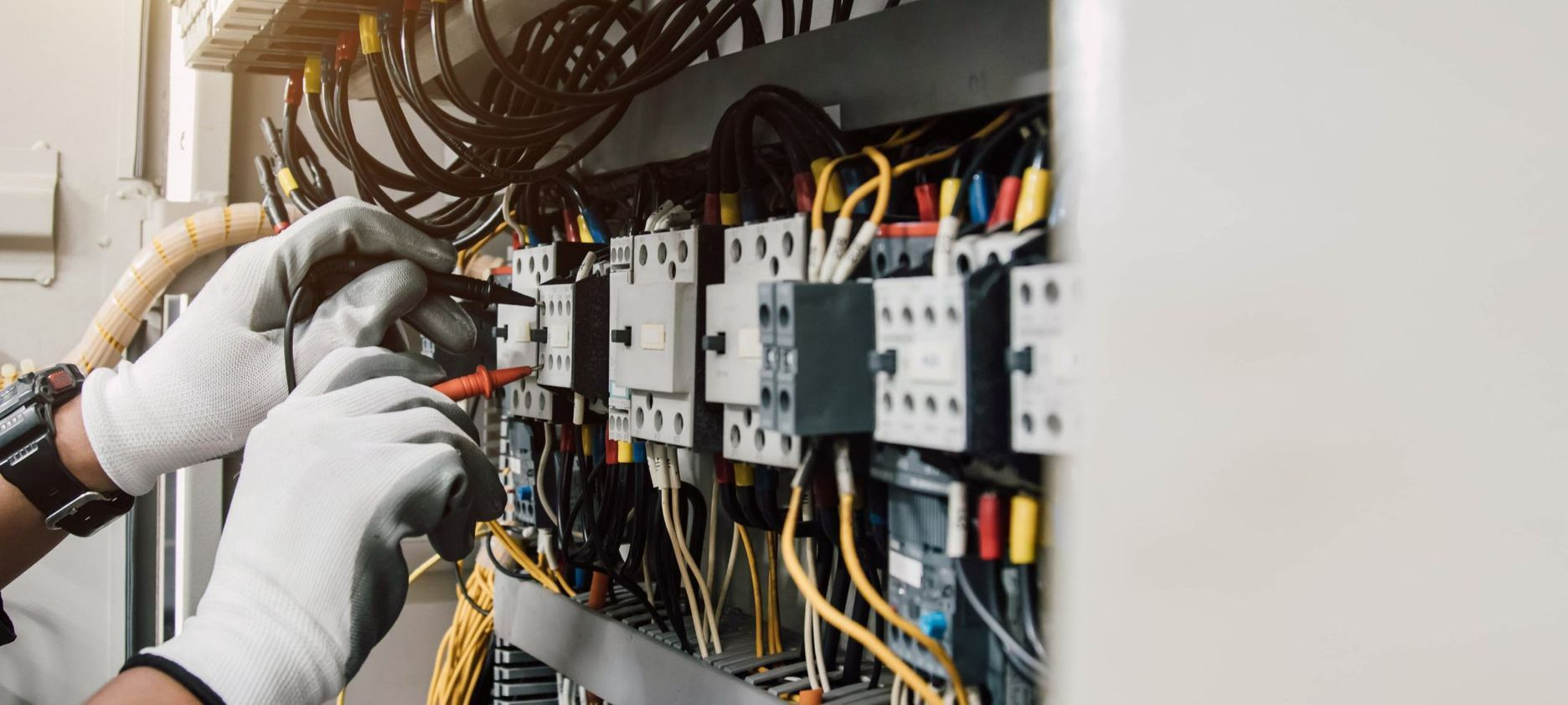 An Electrician is Working on an Electrical Box With a Voltage Tester Pen — Switchboard & Power Controls Pty Ltd in Alice Springs, NT