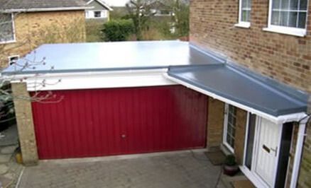 A house with a red garage door and a canopy over it. With a new Flat Roof fitted by Nigel Hayman Roofing.