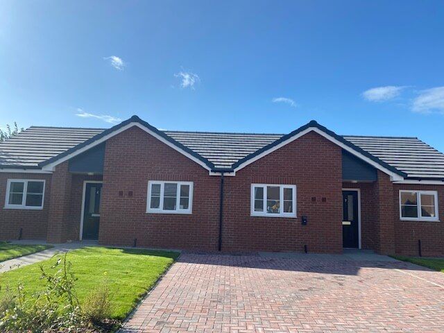 A brick house with a driveway and a blue sky in the background