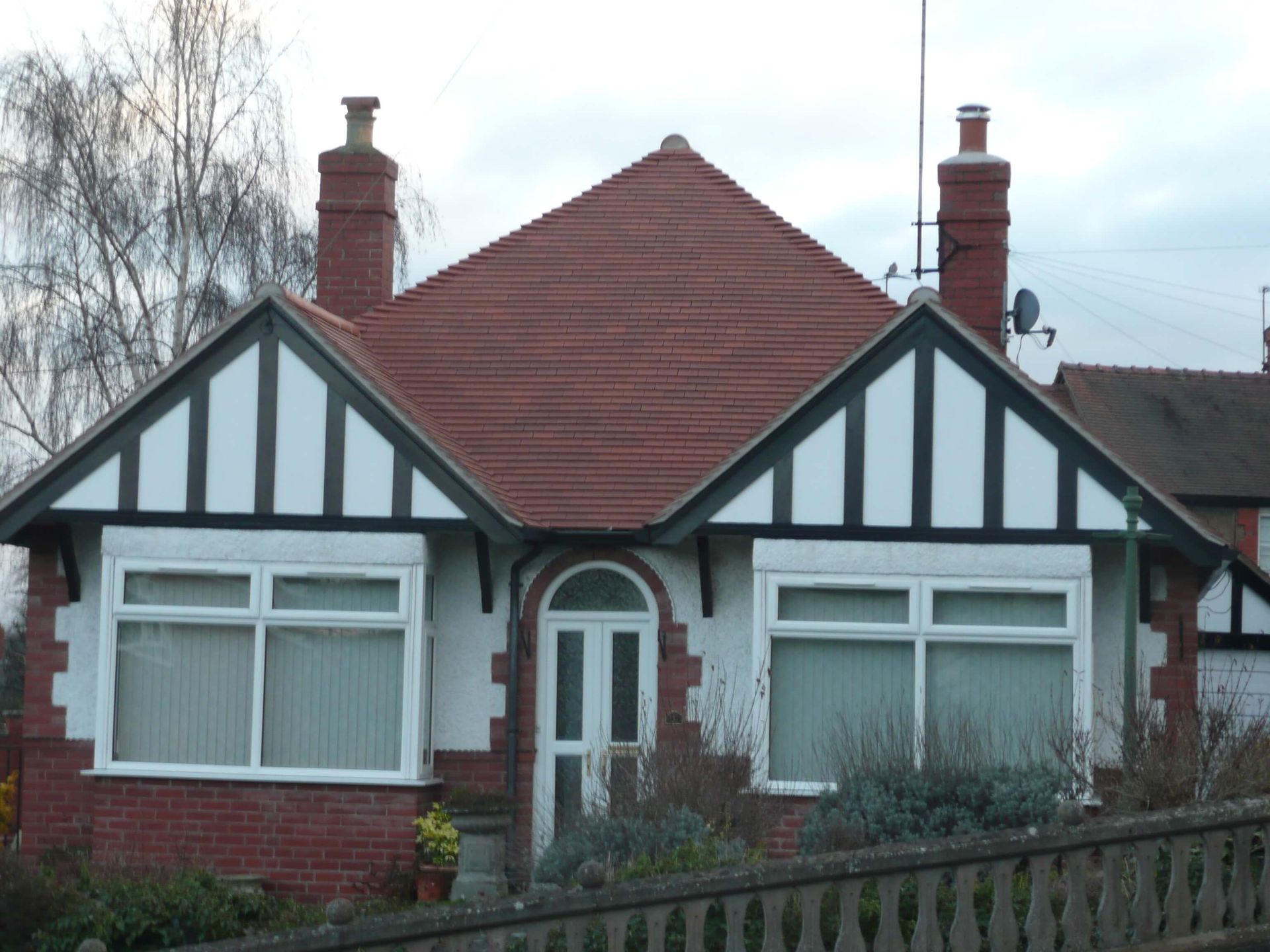 A brick house with a red roof and white trim