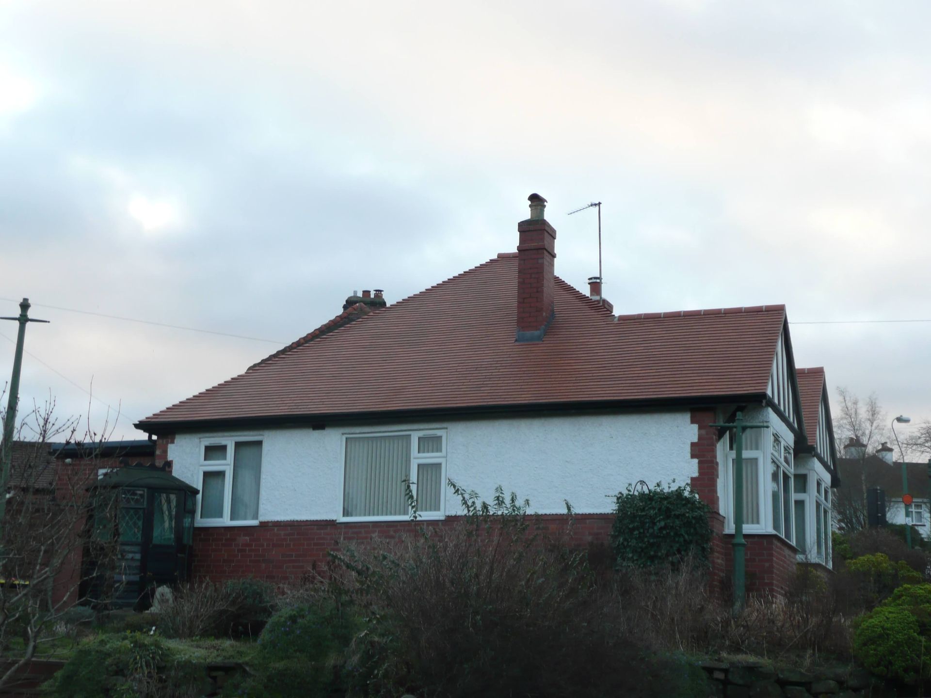 A white house with a red tiled roof and chimneys