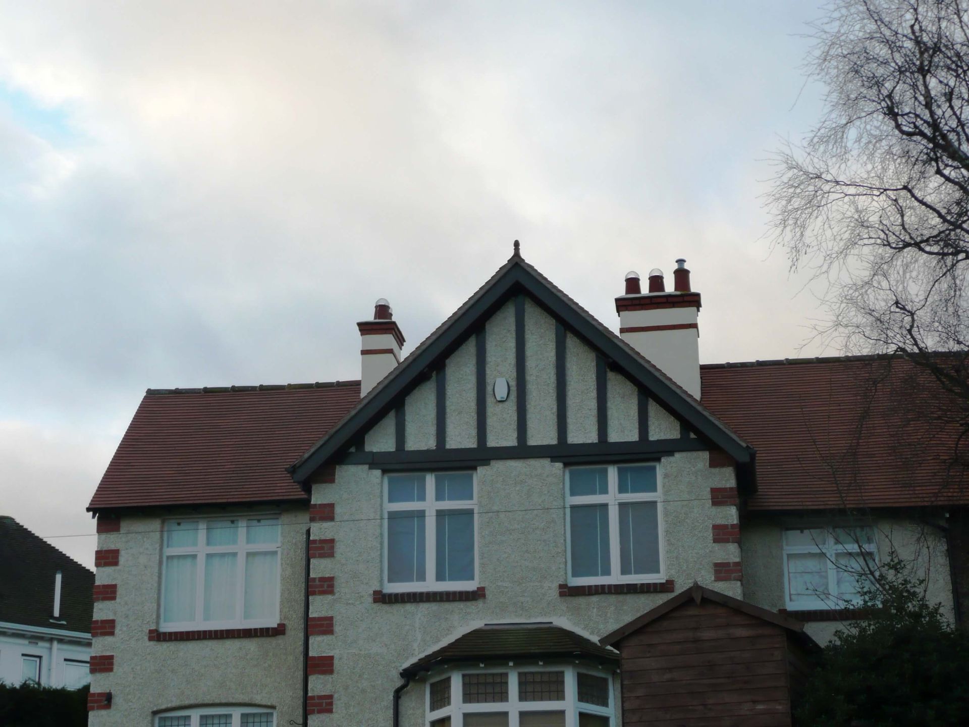 A large white house with a new red tiled roof, fitted by Nigel Hayman Roofing.
