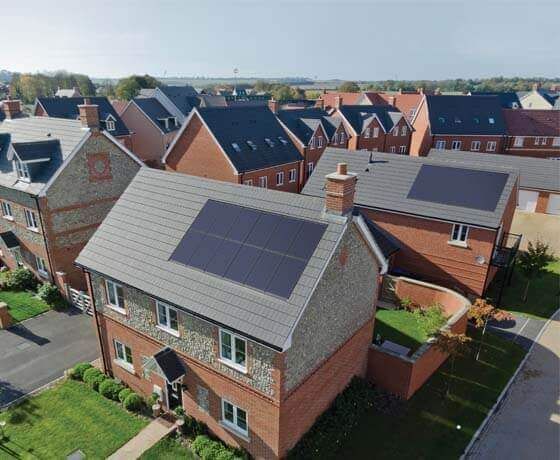 An aerial view of a residential area with houses and solar panels on the roofs.