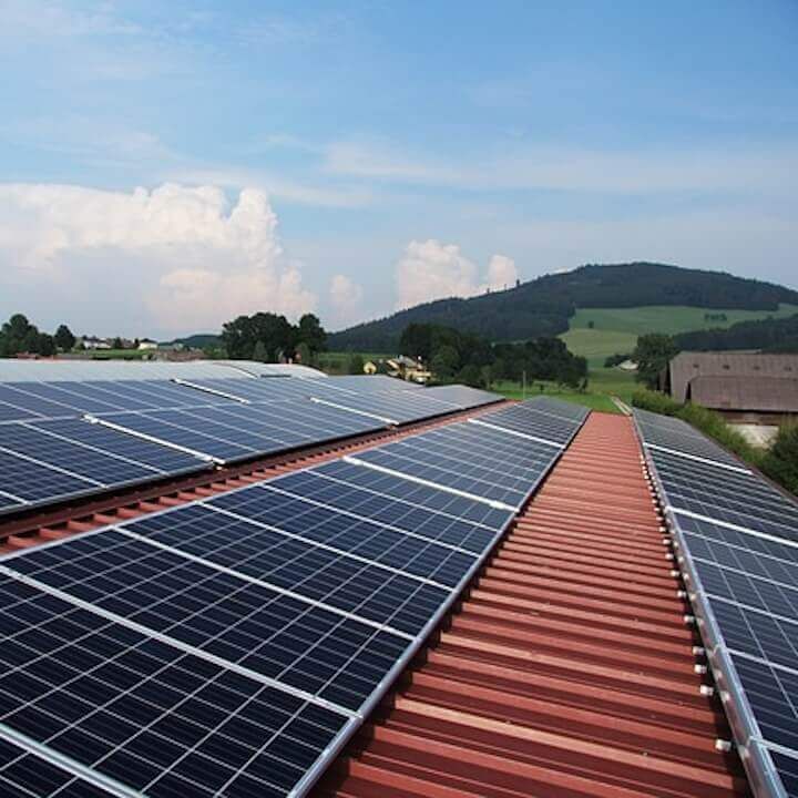 A row of solar panels on a roof with mountains in the background
