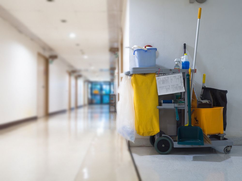 Cleaning Cart In Hallway: Yellow Mop, Blue Bucket, Cleaning Supplies, Near White Wall, Blurred Background — Rocky Commercial Cleaners In Berserker, QLD