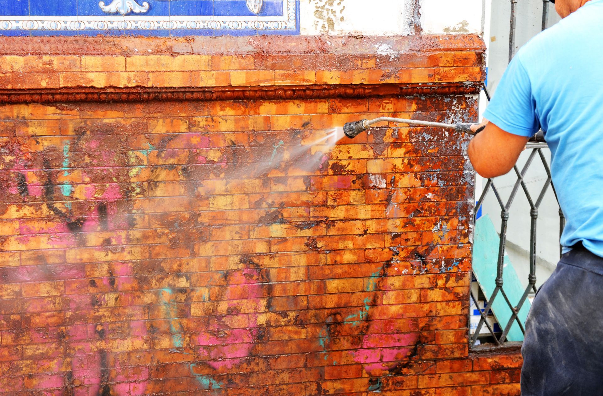 Person Power Washing Graffiti Off A Brick Wall — Rocky Commercial Cleaners In Berserker, QLD