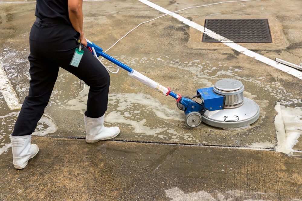 Worker using a floor polisher on a wet concrete surface with cleaning residue. — Rocky Commercial Cleaners In Berserker, QLD