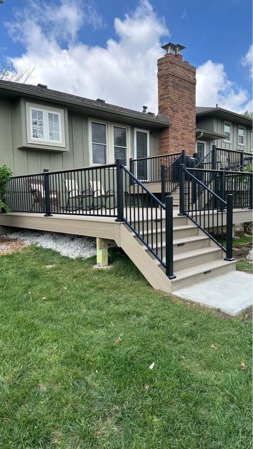 A wooden deck with a metal railing is sitting on top of a house.
