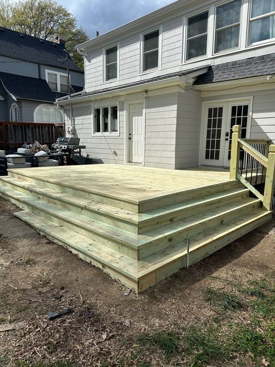 A large wooden deck is sitting in the backyard of a house.