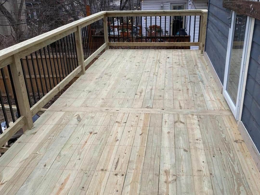 A wooden deck with a metal railing is sitting on top of a house.