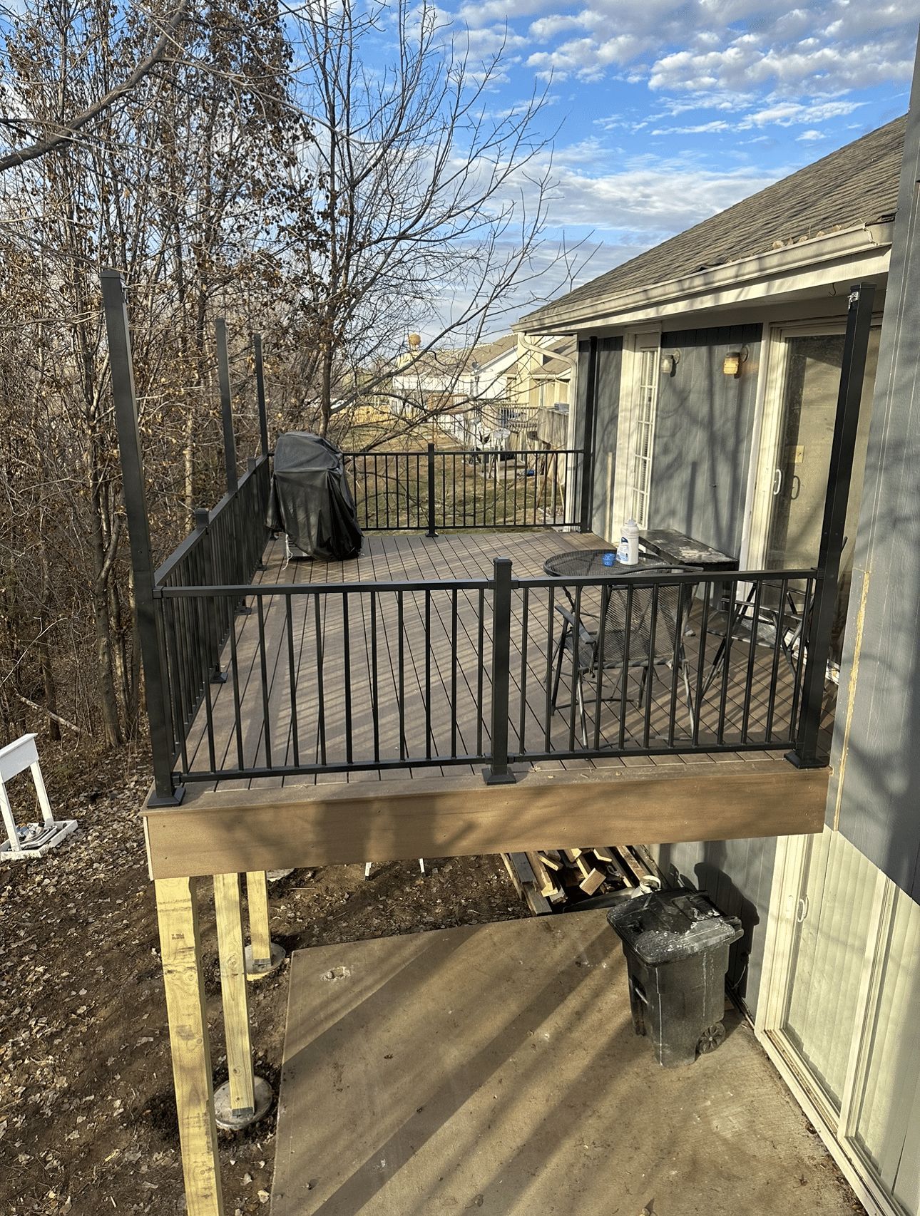A wooden deck with a metal railing is sitting next to a house.