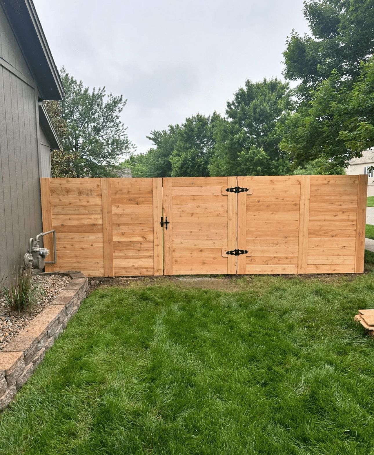 A wooden fence with a gate in the backyard of a house.