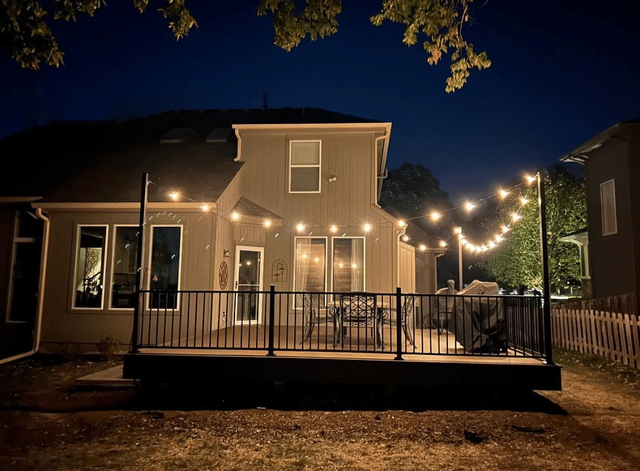 A house with a deck and string lights on it at night.
