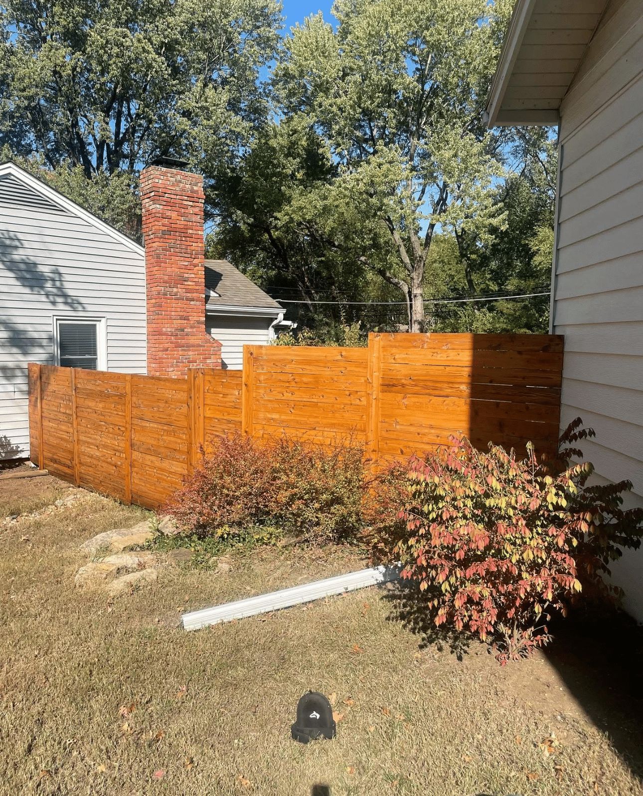 A wooden fence is in the backyard of a house.