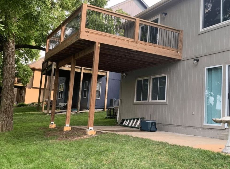 A large wooden deck is sitting in the backyard of a house.