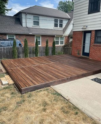 A wooden deck is in front of a brick house.