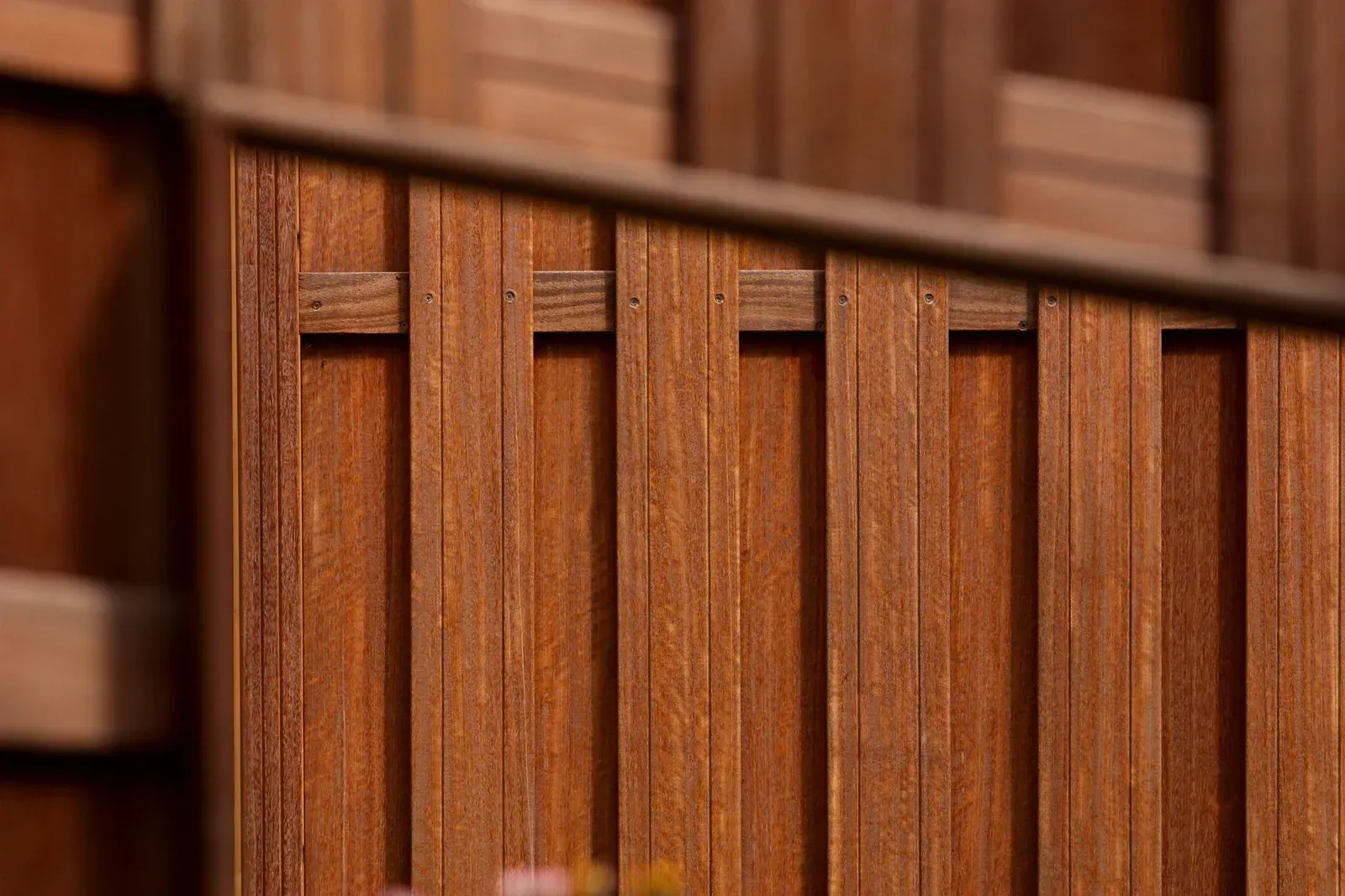 A wooden fence is in the backyard of a house.