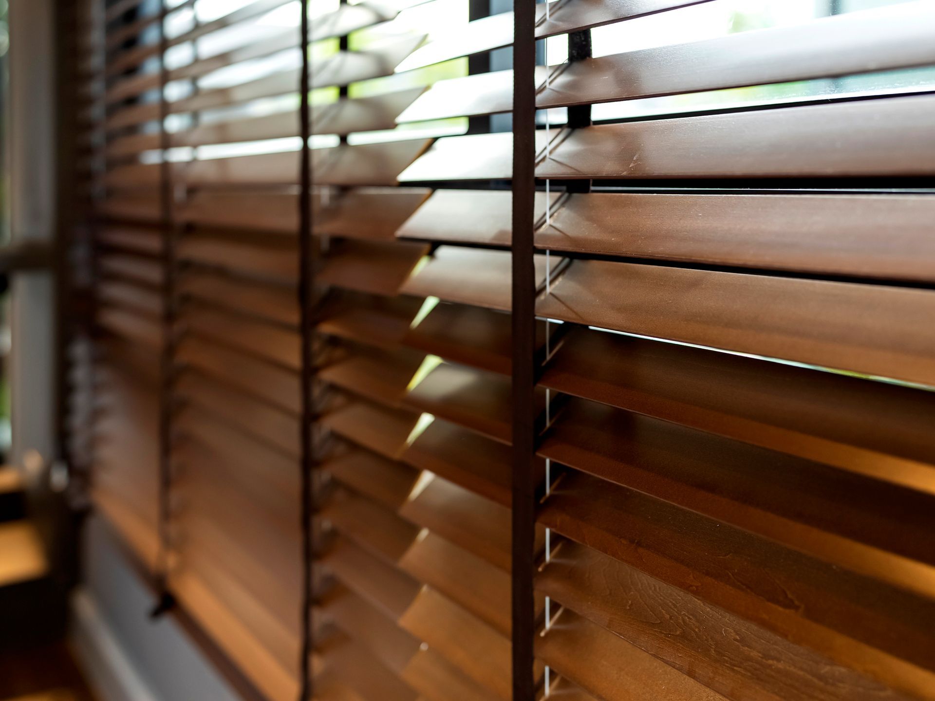 Wooden window shutter blinds allowing sunlight into a home interior, enhancing the space's warmth.