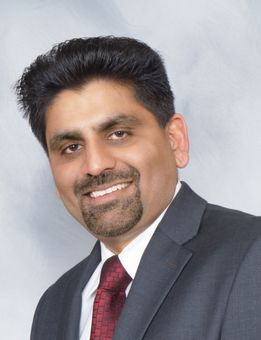 A man in a suit and tie is smiling for the camera