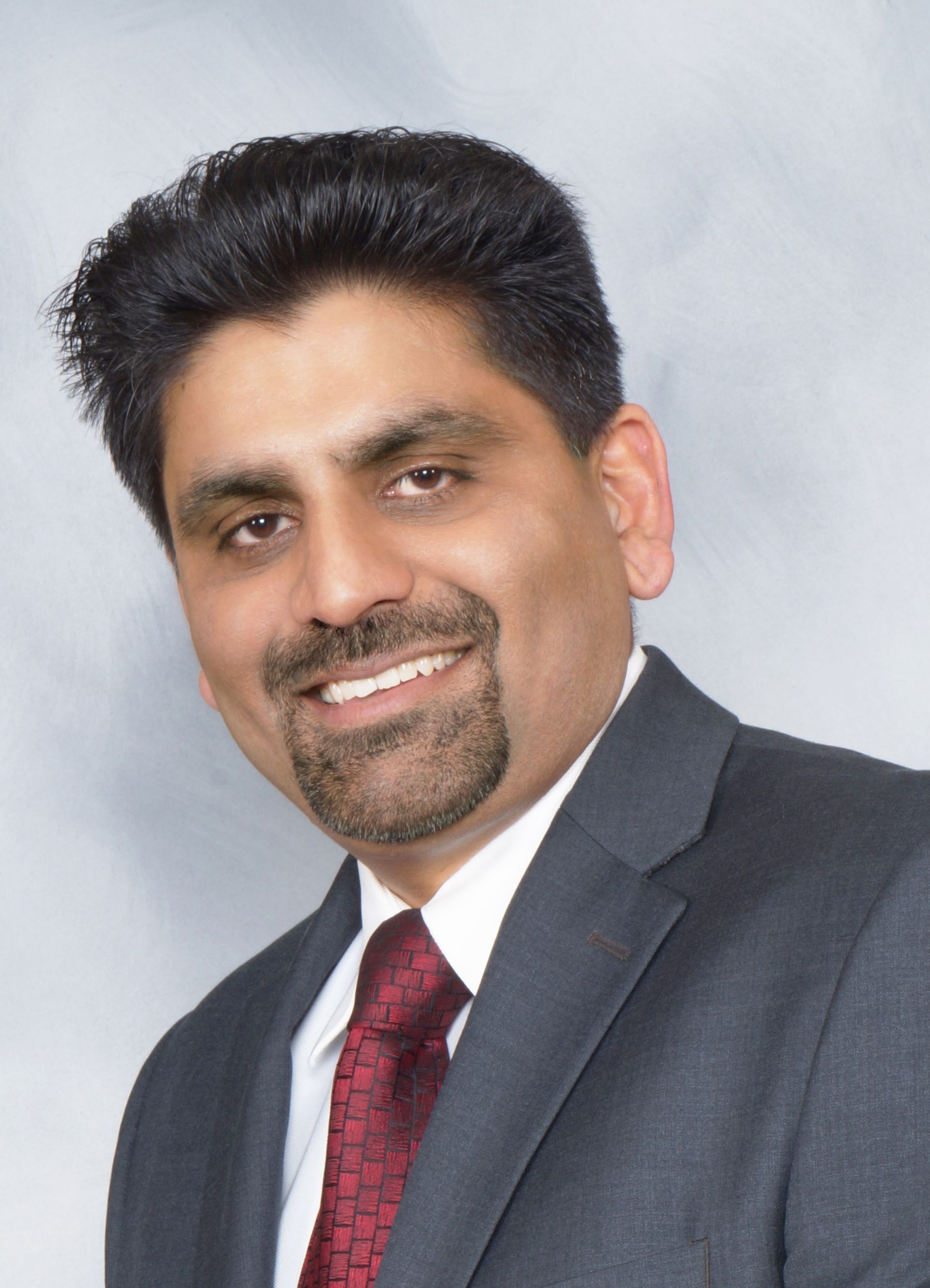 A man in a suit and tie is smiling for the camera