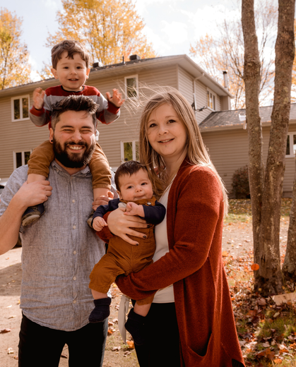 A family is posing for a picture in front of a house.