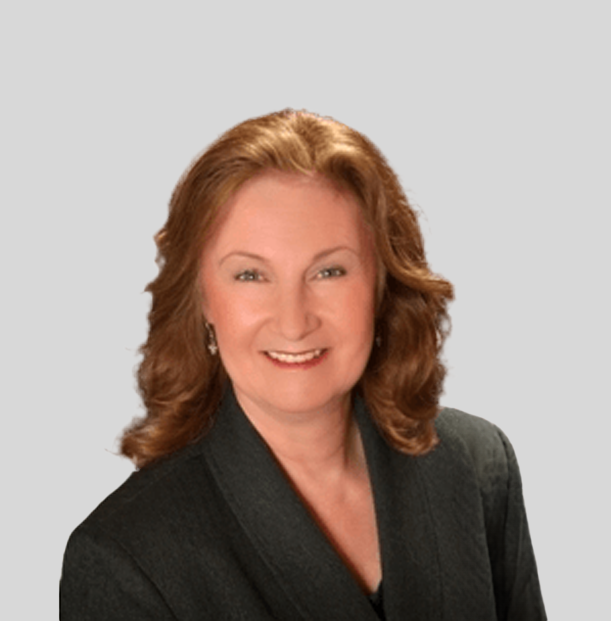 A woman wearing a black jacket and earrings smiles for the camera