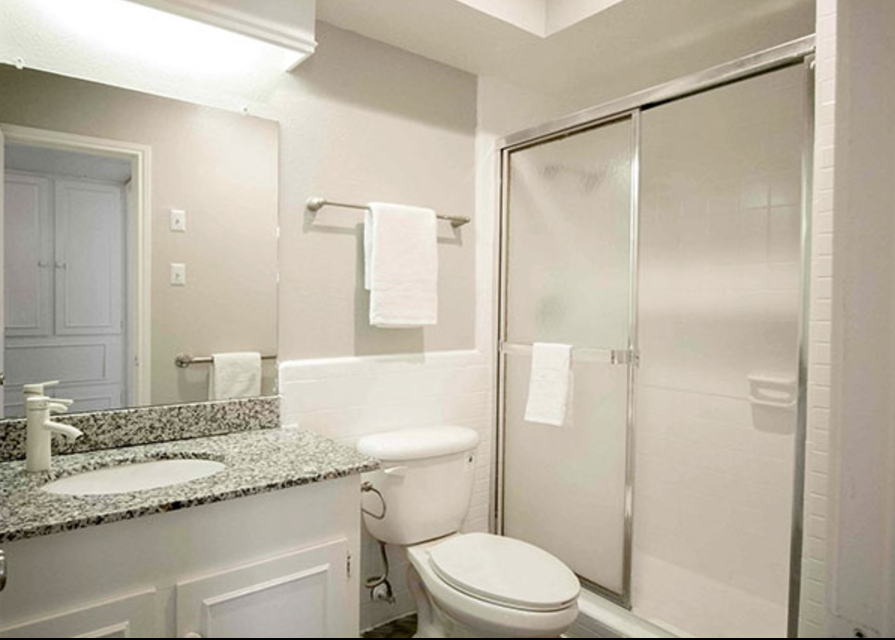 A bathroom with a toilet , sink and shower.