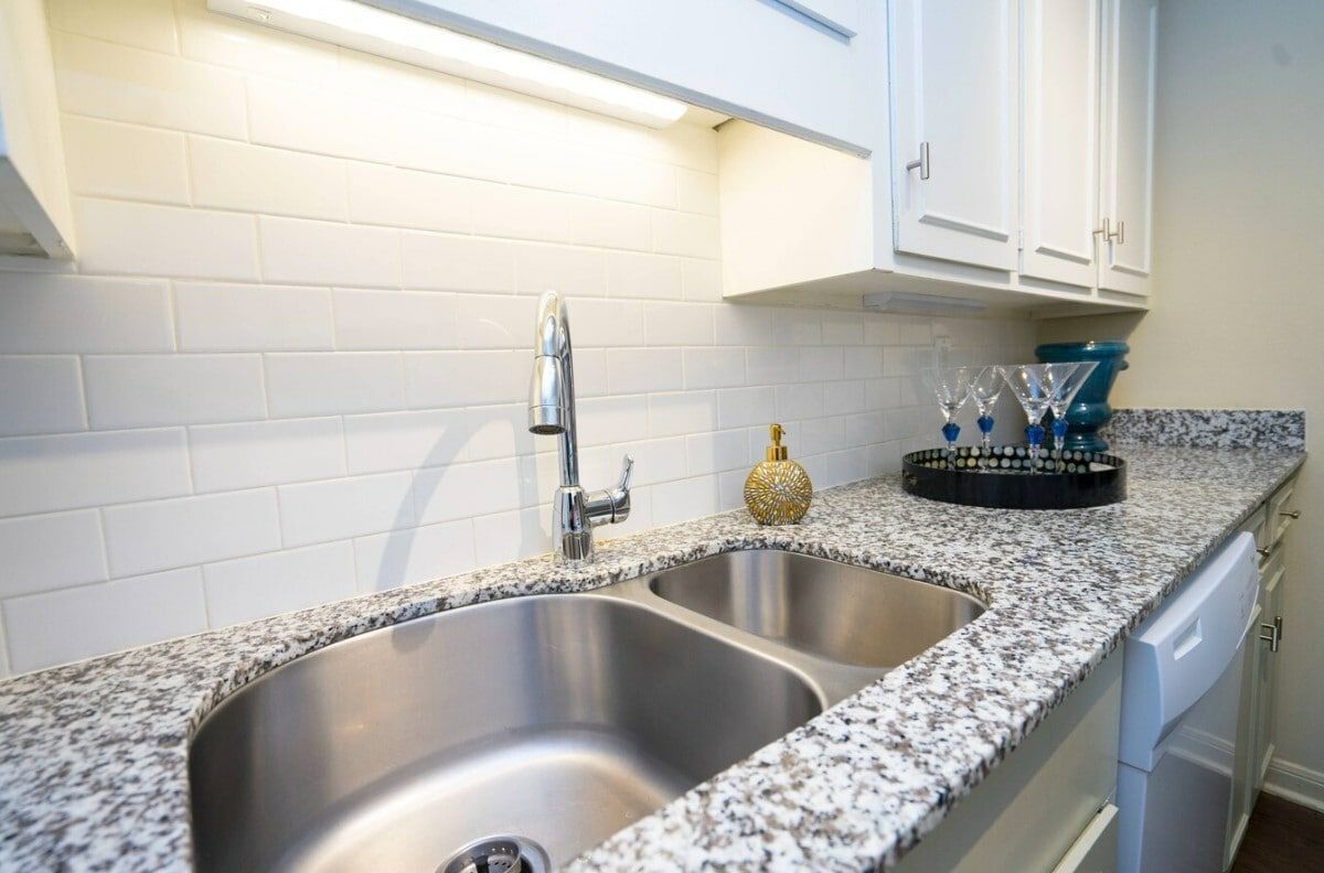 A kitchen with a stainless steel sink and granite counter tops.