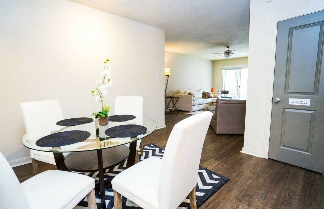 A dining room with a glass table and white chairs.