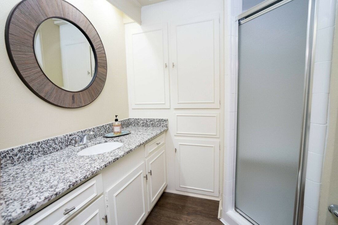A bathroom with a sink , mirror , and walk in shower.