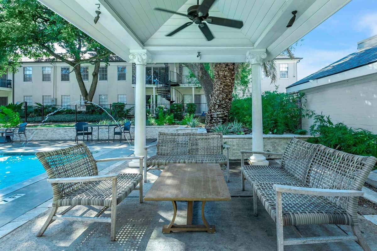 A gazebo with a table and chairs underneath it next to a pool.