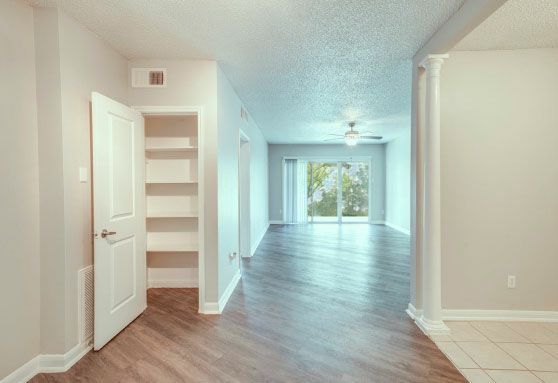 An empty apartment with hardwood floors and a sliding glass door.